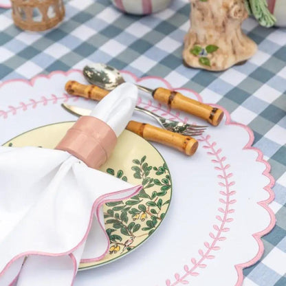 Arrow placemat with pink scalloped edge on tablecloth beside botanical plate and bamboo flatware on Tampa Home & Garden Store