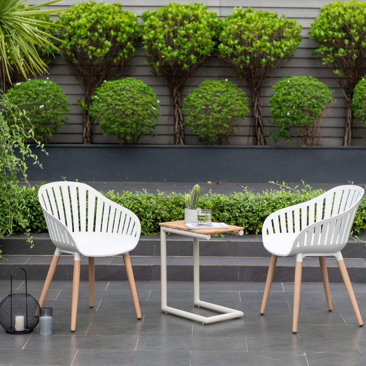 Portals Light C-shape Chair Set: two white outdoor chairs with wooden legs on a gray patio on Tampa Home & Garden Store