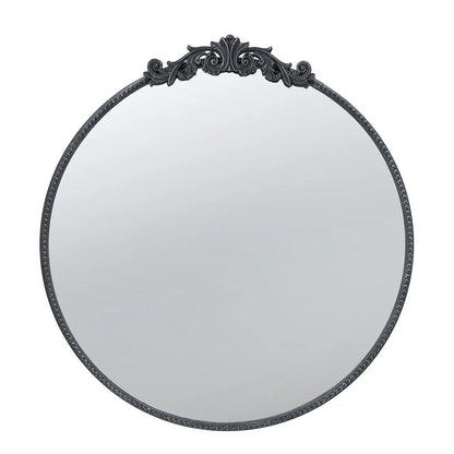 Round wall mirror with a dark metal Baroque-inspired frame and decorative top crest on Tampa Home & Garden Store