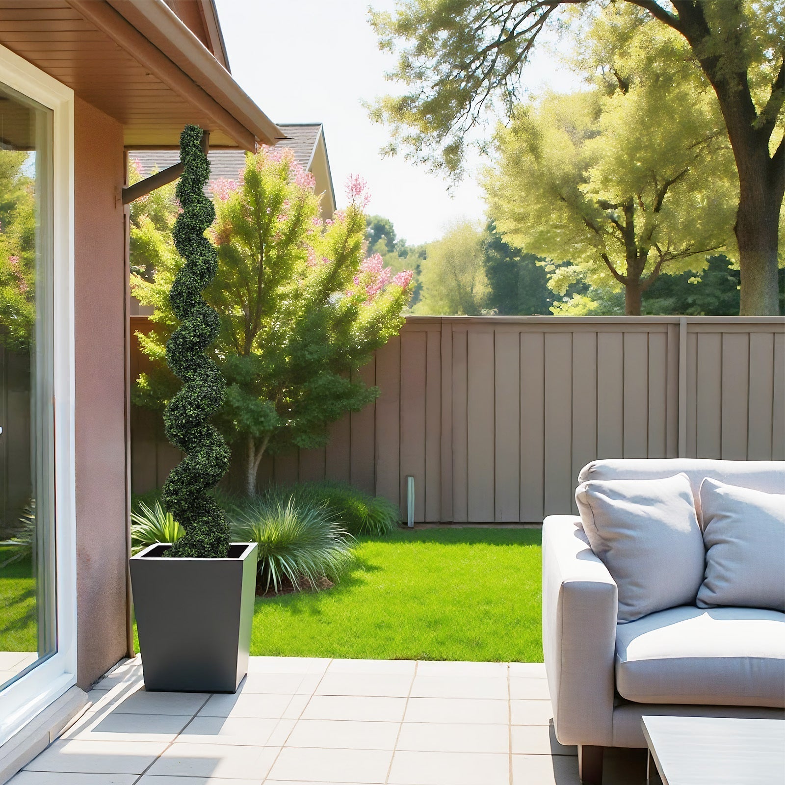 Faux spiral topiary in a tall square gray planter on a sunny backyard patio on Tampa Home & Garden Store