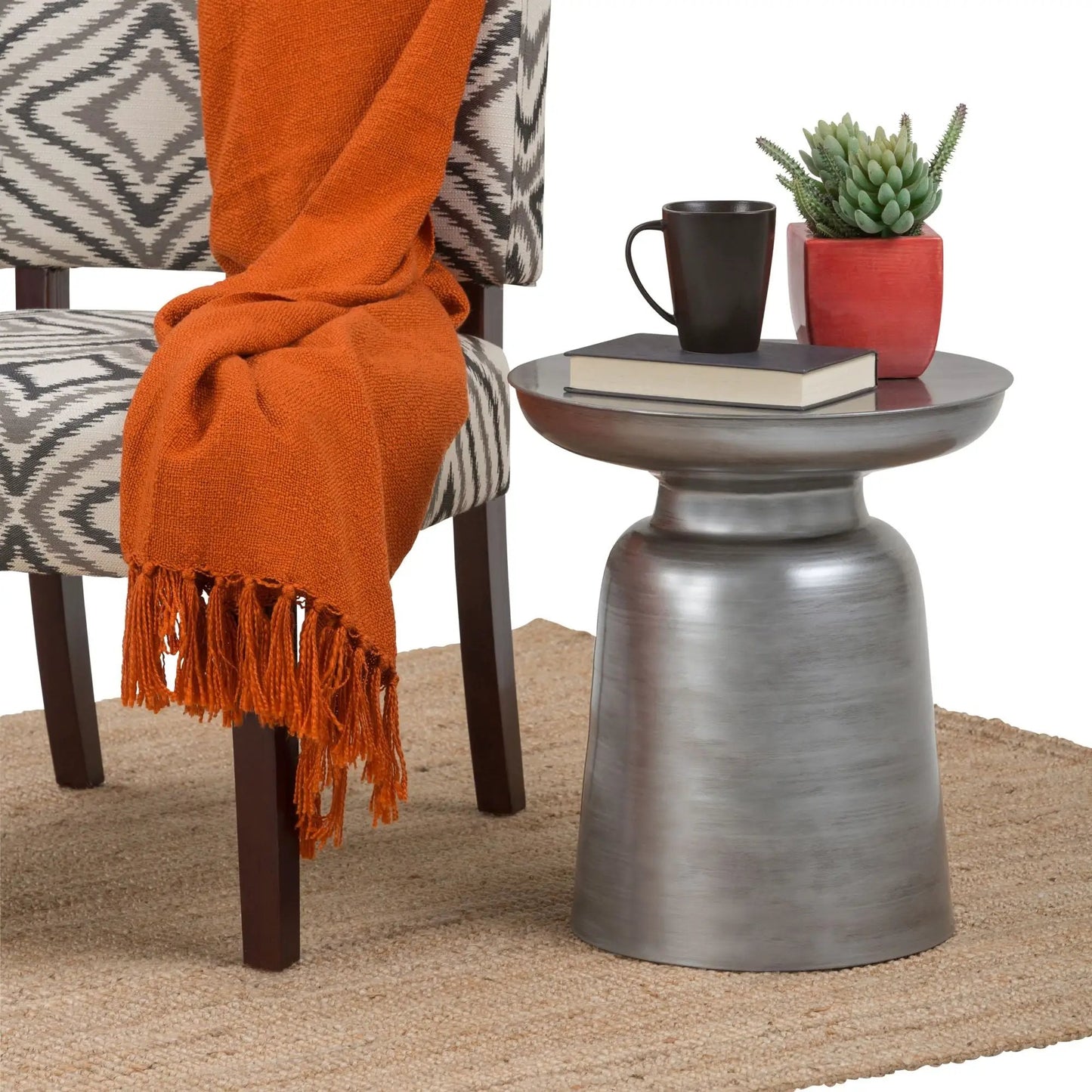 Toby Handcrafted Metal Accent Table with brushed finish, shown with mug, planter and two books on Tampa Home & Garden Store