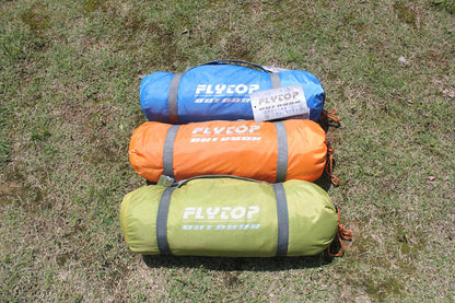 Flytop outdoor camping tents rolled in blue, orange, and olive sacks with logo on grass on Tampa Home & Garden Store
