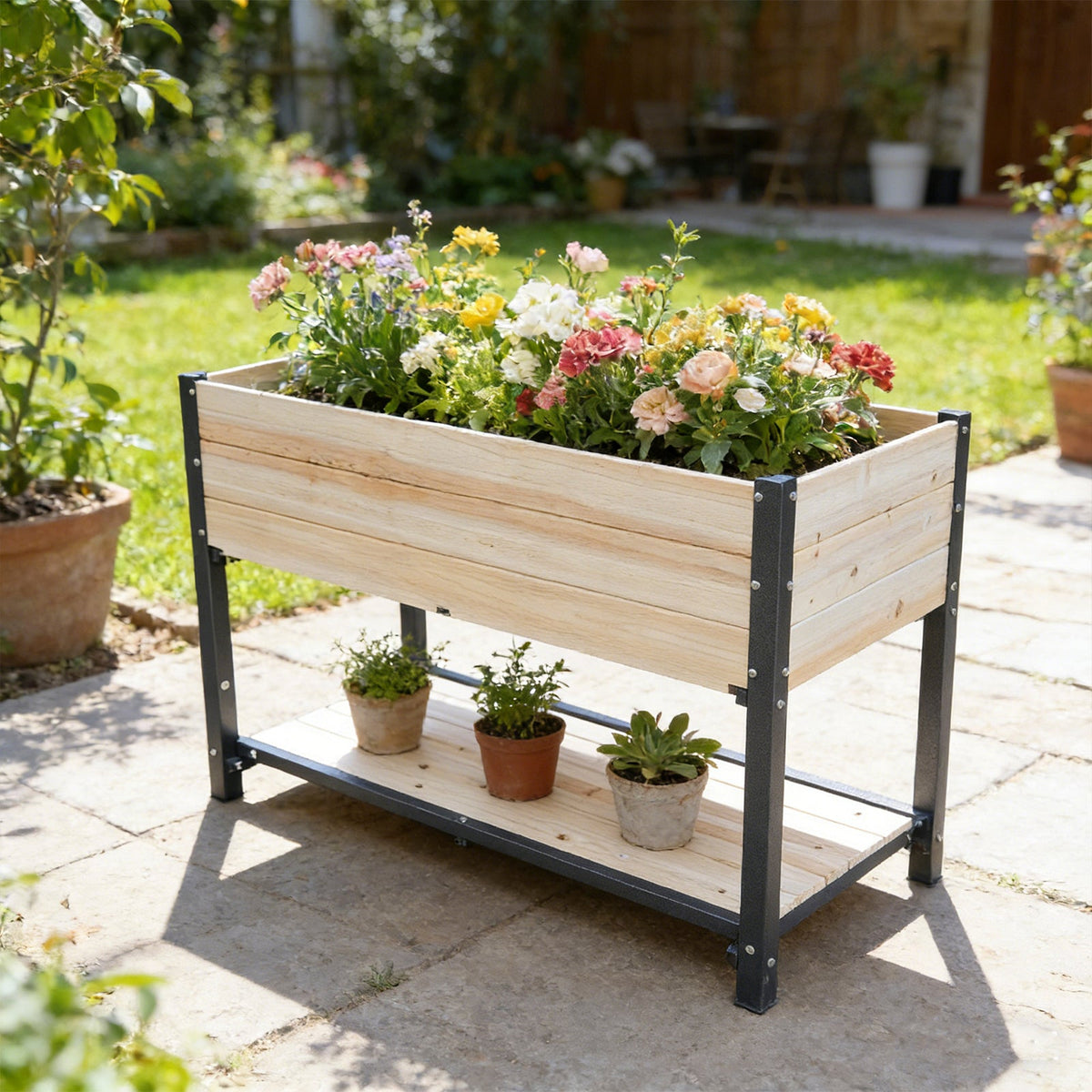 Solid wood raised garden bed with black iron frame in natural wood by HouseOfZazla, filled with colorful flowers and 4 pots on lower shelf on Tampa Home & Garden Store