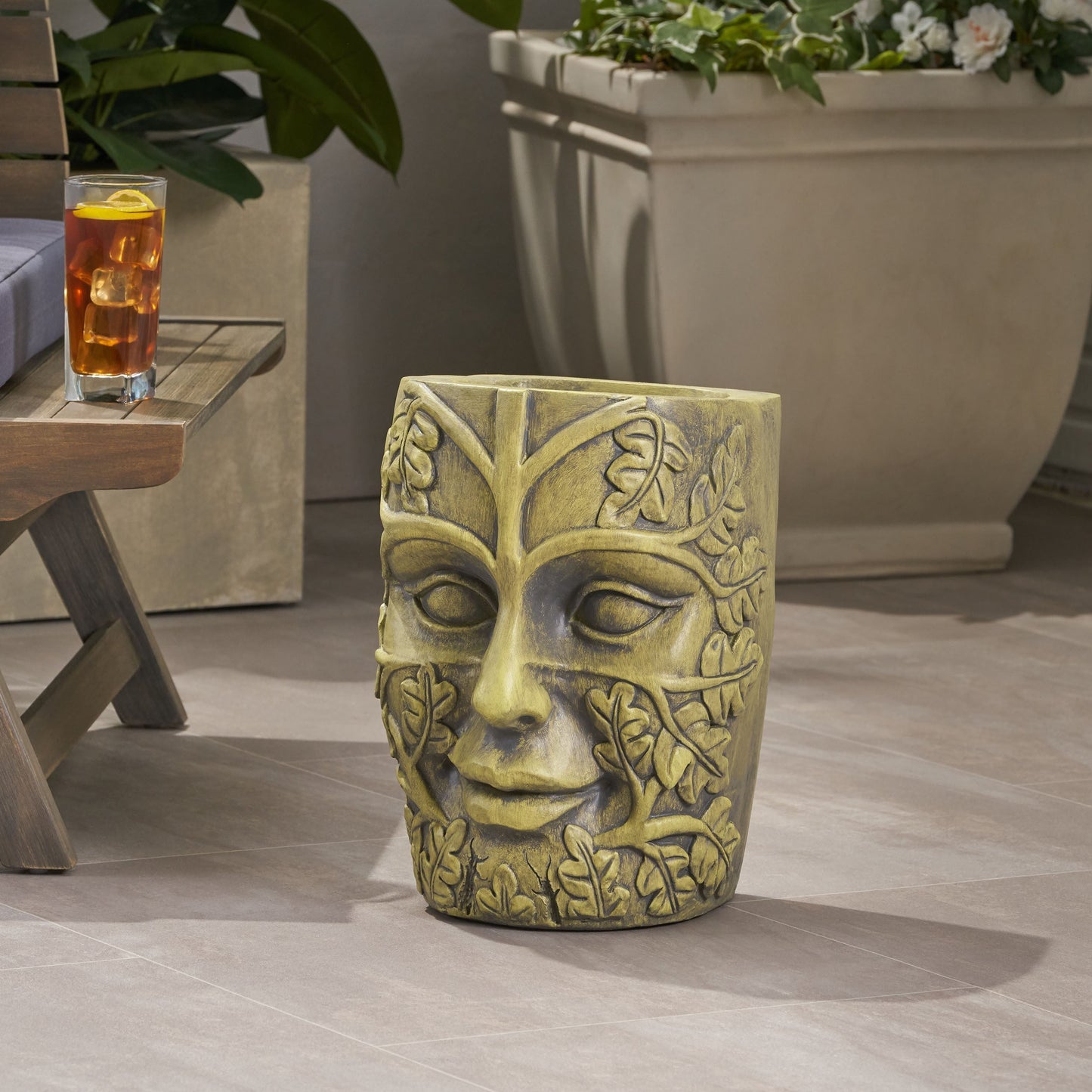 Garden urn planter with a carved face and ivy vine pattern in weathered stone finish on Tampa Home & Garden Store