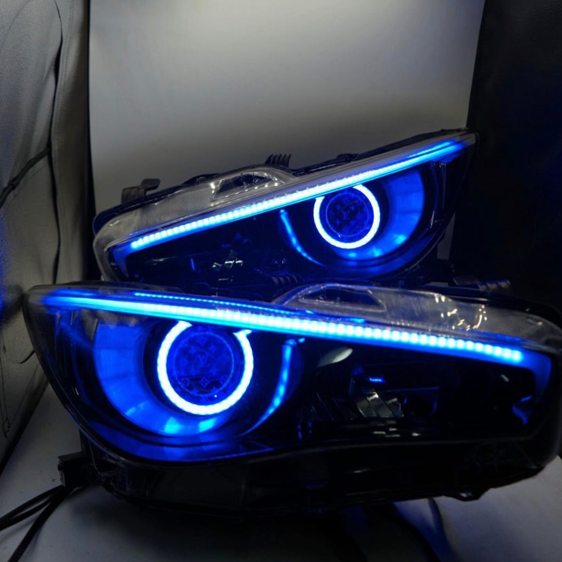 Pair of Infiniti Q50 RGBW Flow Series LED DRL boards with blue halo rings and top LED strip on Tampa Home & Garden Store