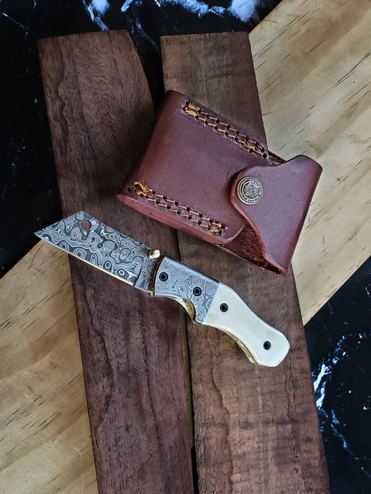 TF-007 Titan Damascus knife with white handle and leather sheath on wood board on Tampa Home & Garden Store