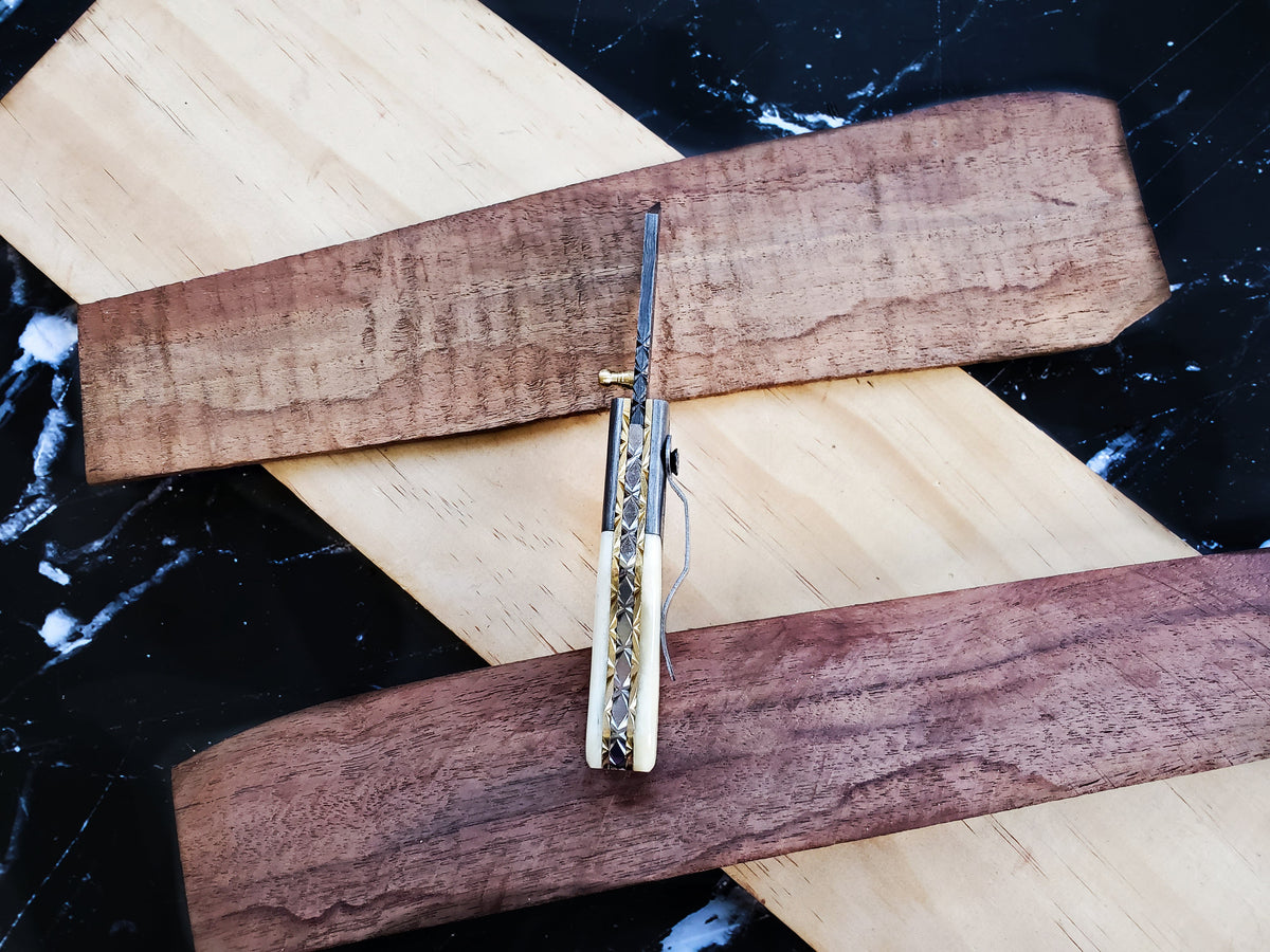 TF-007 Titan knife with patterned blade and ivory handle on wood planks on Tampa Home & Garden Store