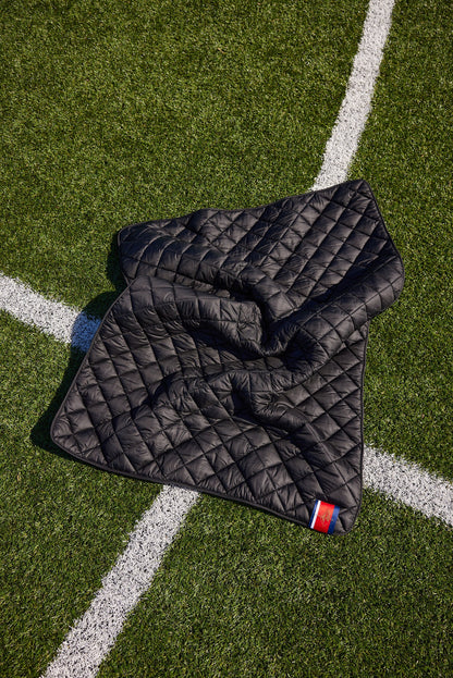 Iowa State University black quilted puffer blanket on football field with a corner tag on Tampa Home & Garden Store