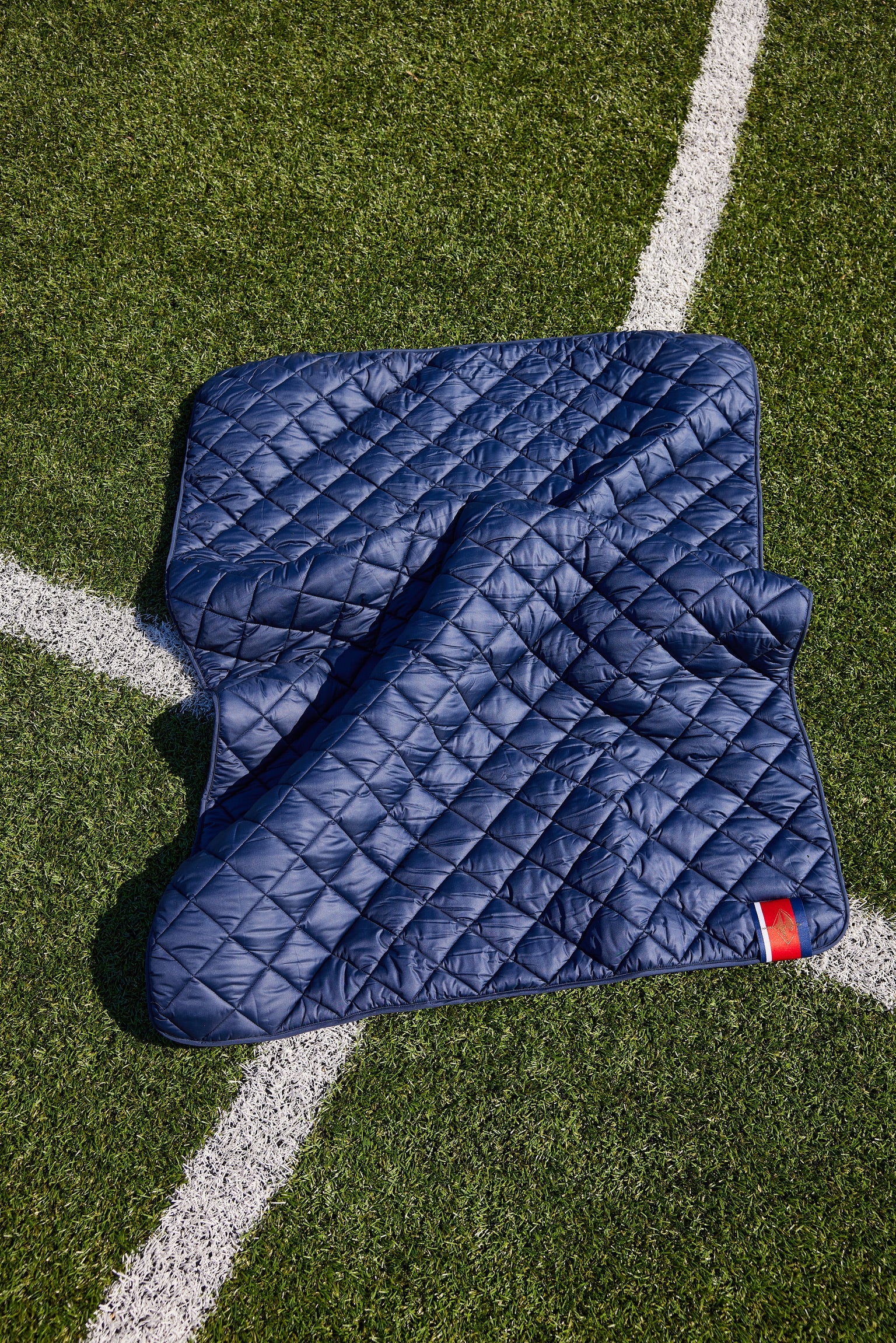 Villanova Navy Puffer Blanket by Pretty Rugged, quilted navy on turf with white line on Tampa Home & Garden Store