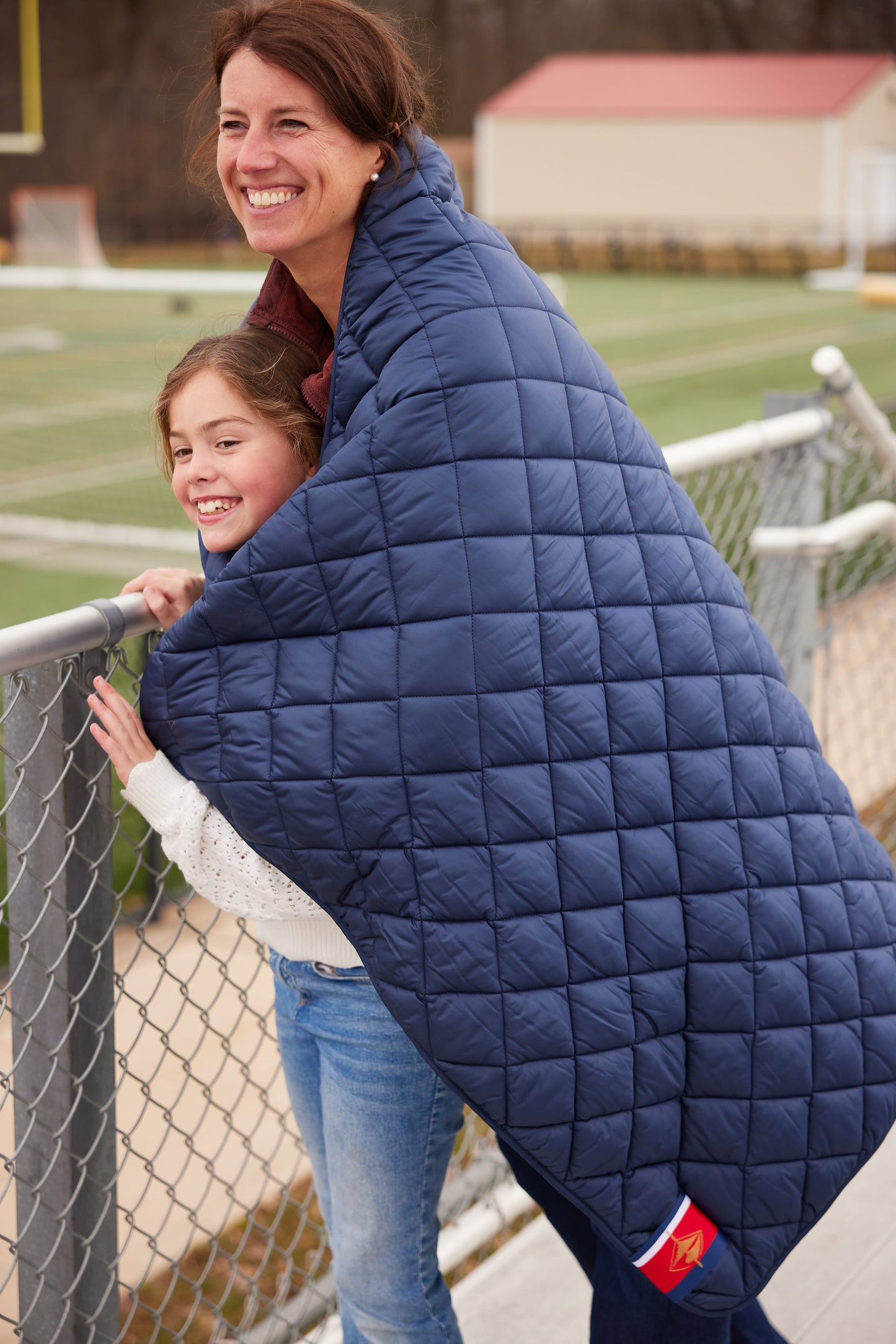 Beach Day navy quilted puffer blanket by Pretty Rugged draped over two people outdoors on Tampa Home & Garden Store