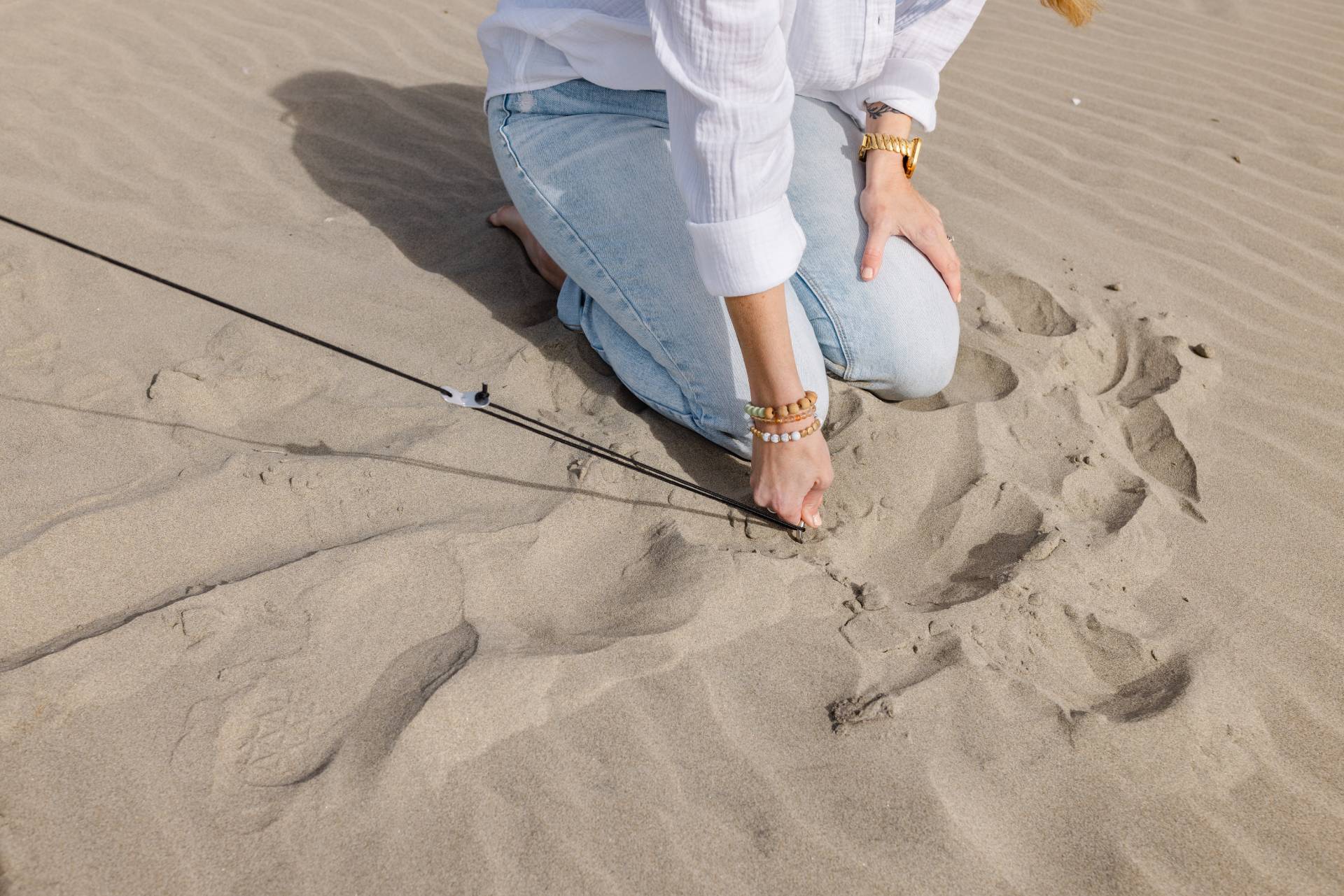 Pop 'N Go Canopy on sandy beach with a kneeling person in light jeans and white shirt on Tampa Home & Garden Store