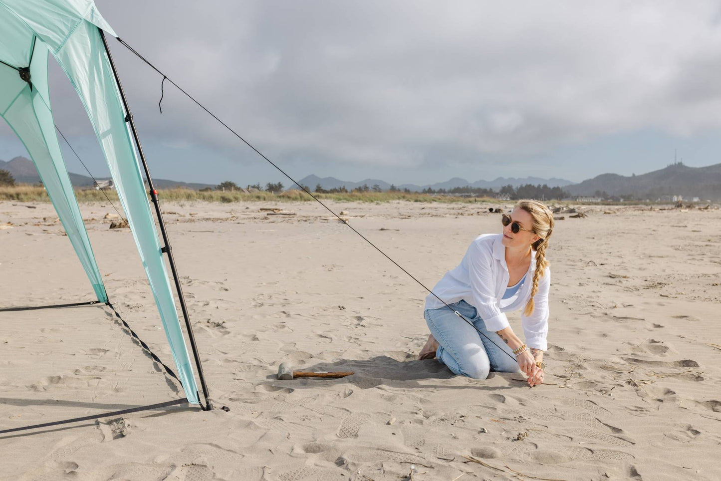 Pop 'N Go canopy mint-green with black poles on a sandy beach beside a kneeling woman on Tampa Home & Garden Store