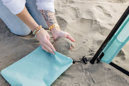 Pop 'N Go Canopy turquoise setup on sandy beach with hands adjusting fabric by The California Beach Company LLC on Tampa Home & Garden Store