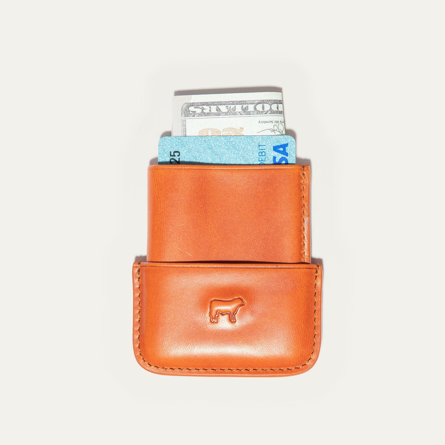 Molded orange leather card case with blue card and dollar bill Will Leather Goods logo on Tampa Home & Garden Store