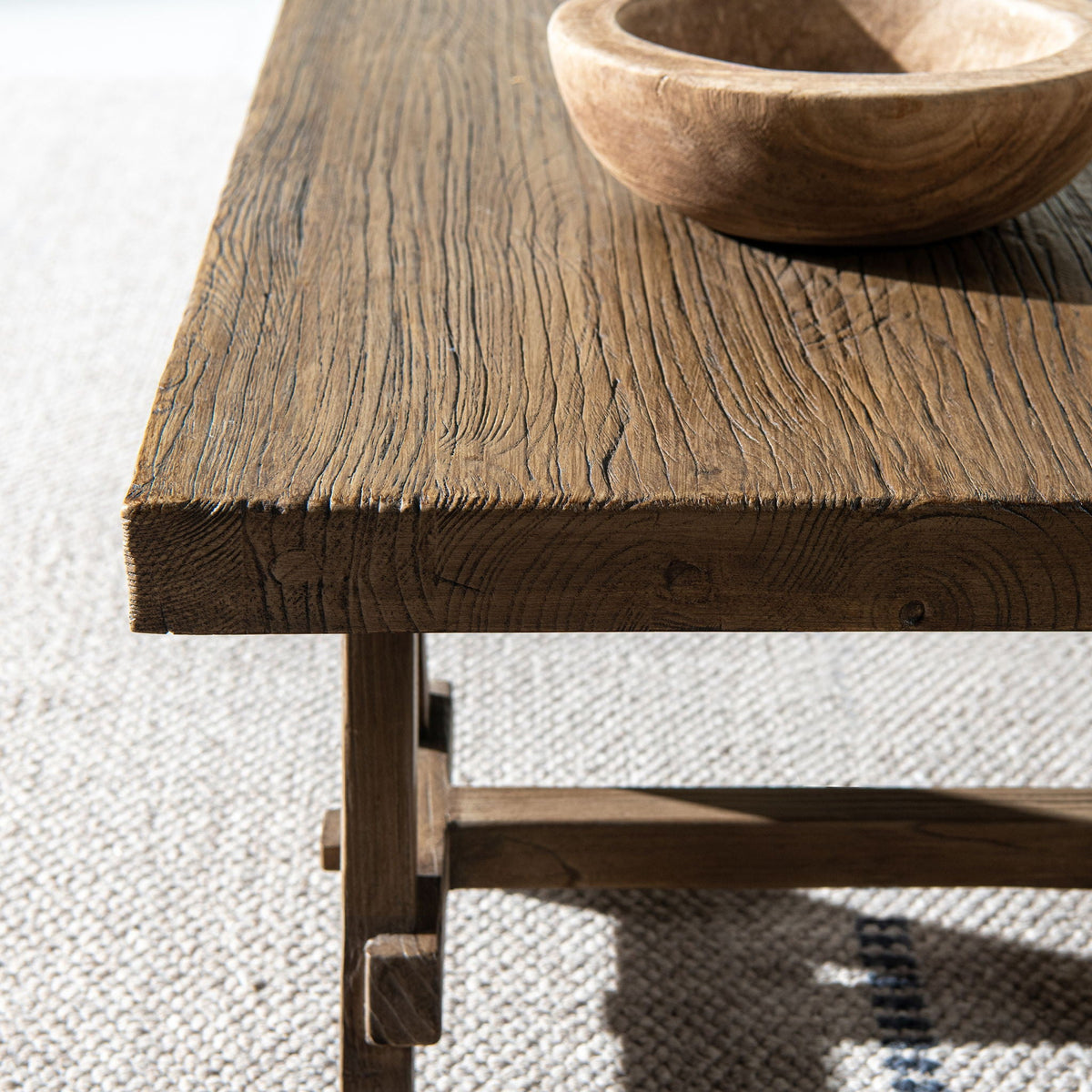 Trestle coffee table in reclaimed elm with brown finish; grain with wooden bowl on Tampa Home & Garden Store