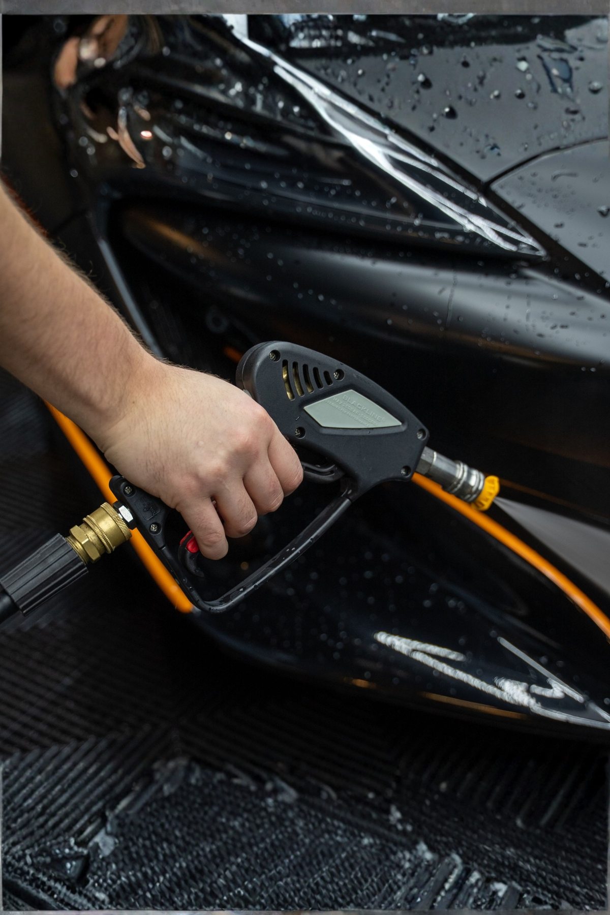BLACKLINE® snub-nose pressure washer gun, black handheld unit with orange hose beside a wet black car on Tampa Home & Garden Store