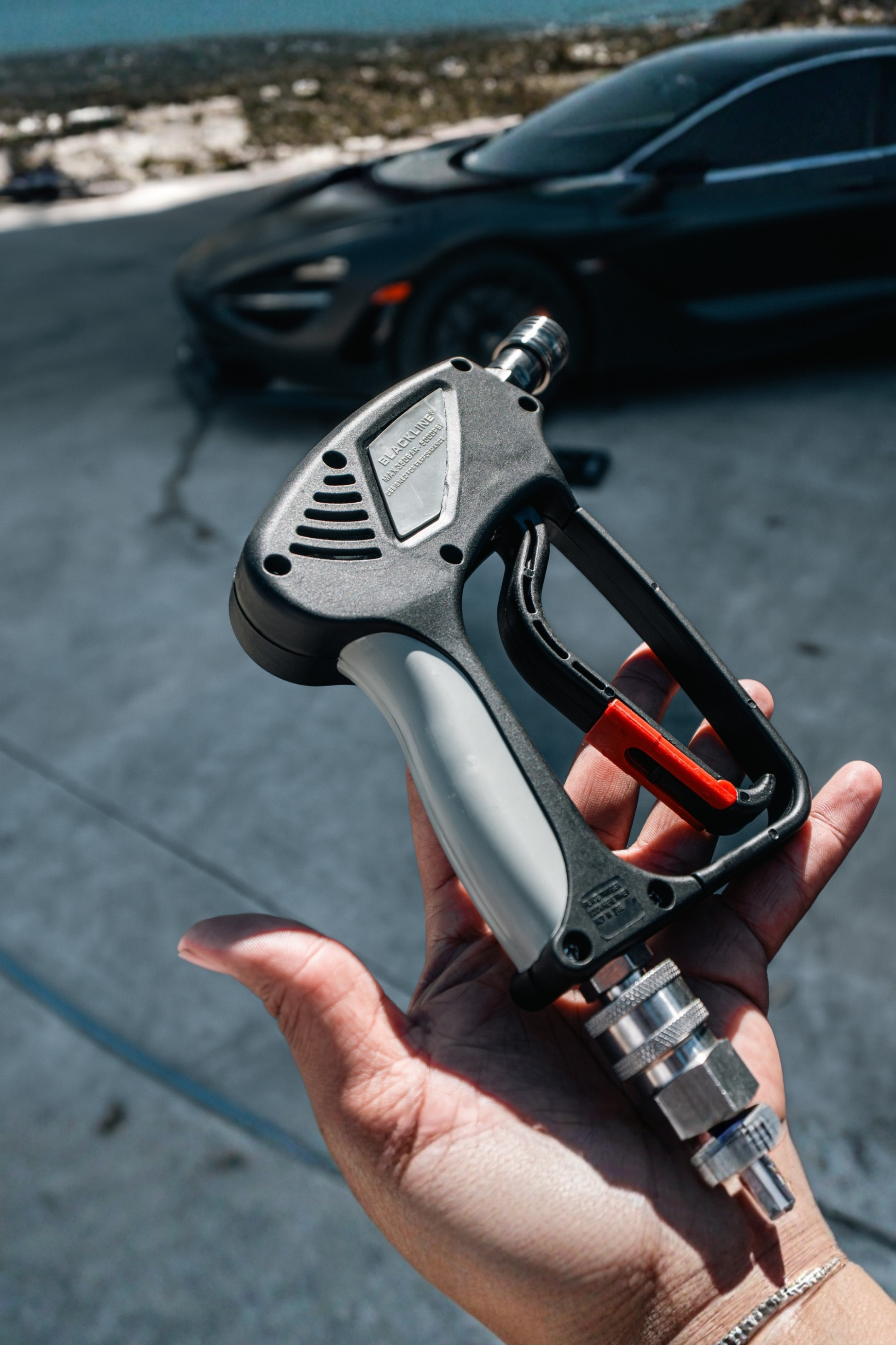 Blackline SNUB-NOSE pressure washer gun in black and gray with red trigger, car in background on Tampa Home & Garden Store