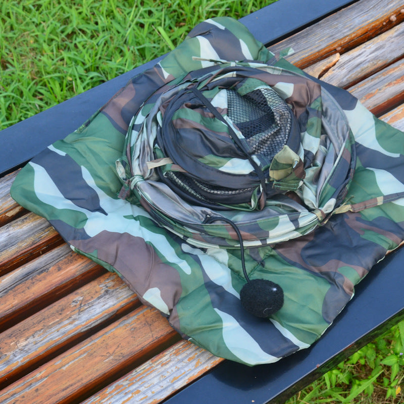 Cat tent in camouflage fabric, collapsed and coiled with a black pom-pom toy on a bench on Tampa Home & Garden Store