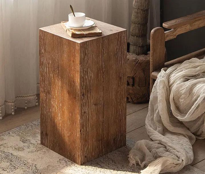 Solid wood square side table in brown beside a bed with a cup on top on Tampa Home & Garden Store