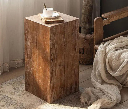 Solid wood square side table in brown beside a bed with a cup on top on Tampa Home & Garden Store