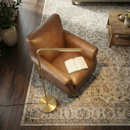 Verve floor lamp with gold finish and curved arm; round base beside a leather chair on Tampa Home & Garden Store