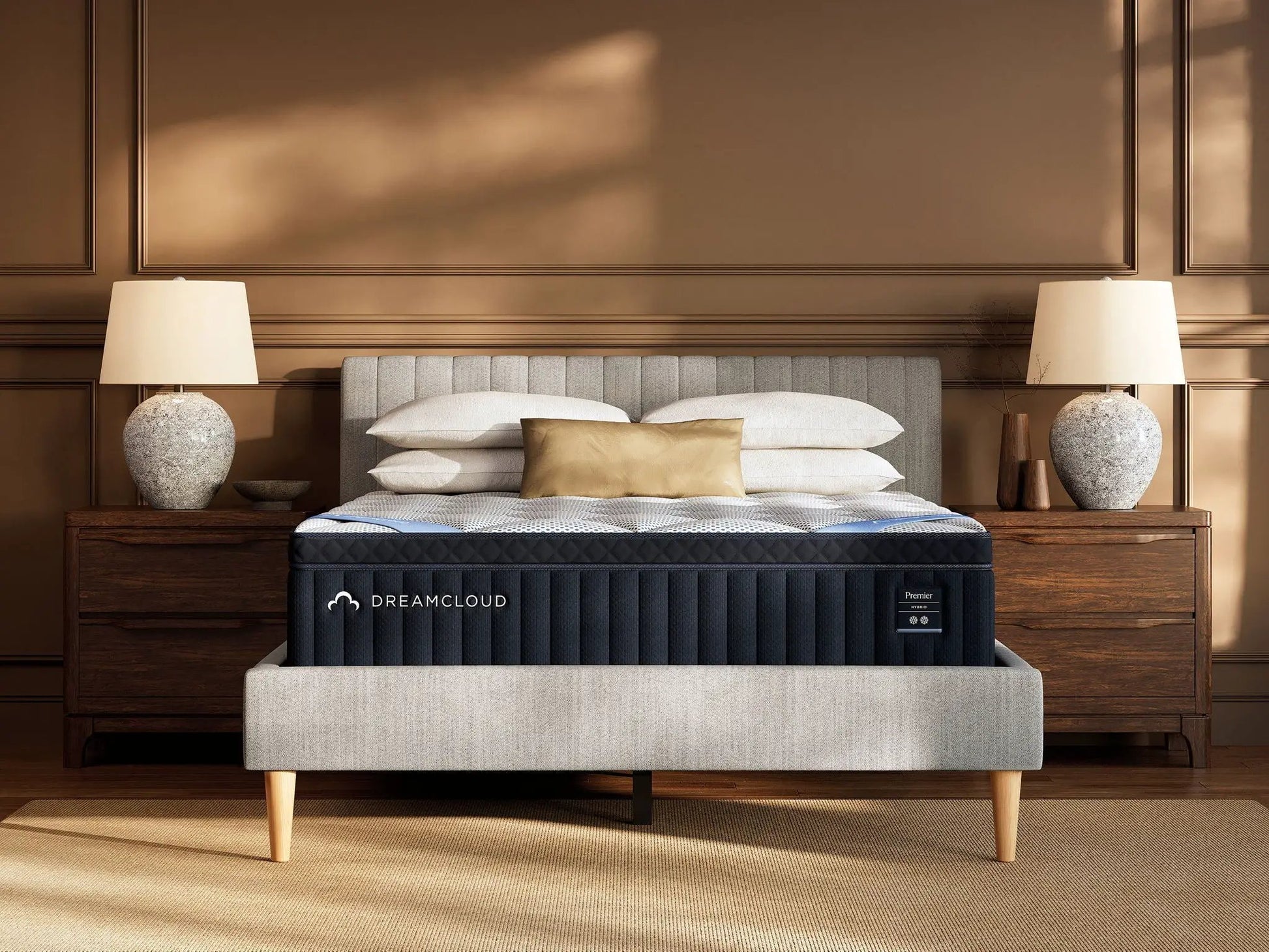 DreamCloud Premier Hybrid mattress on a dark navy fabric bed with beige pillows on Tampa Home & Garden Store