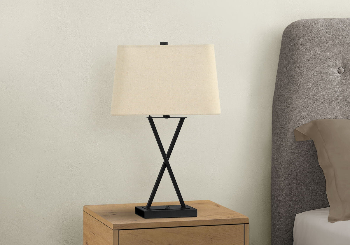 Table lamp with black metal base and beige fabric shade on a wooden nightstand on Tampa Home & Garden Store