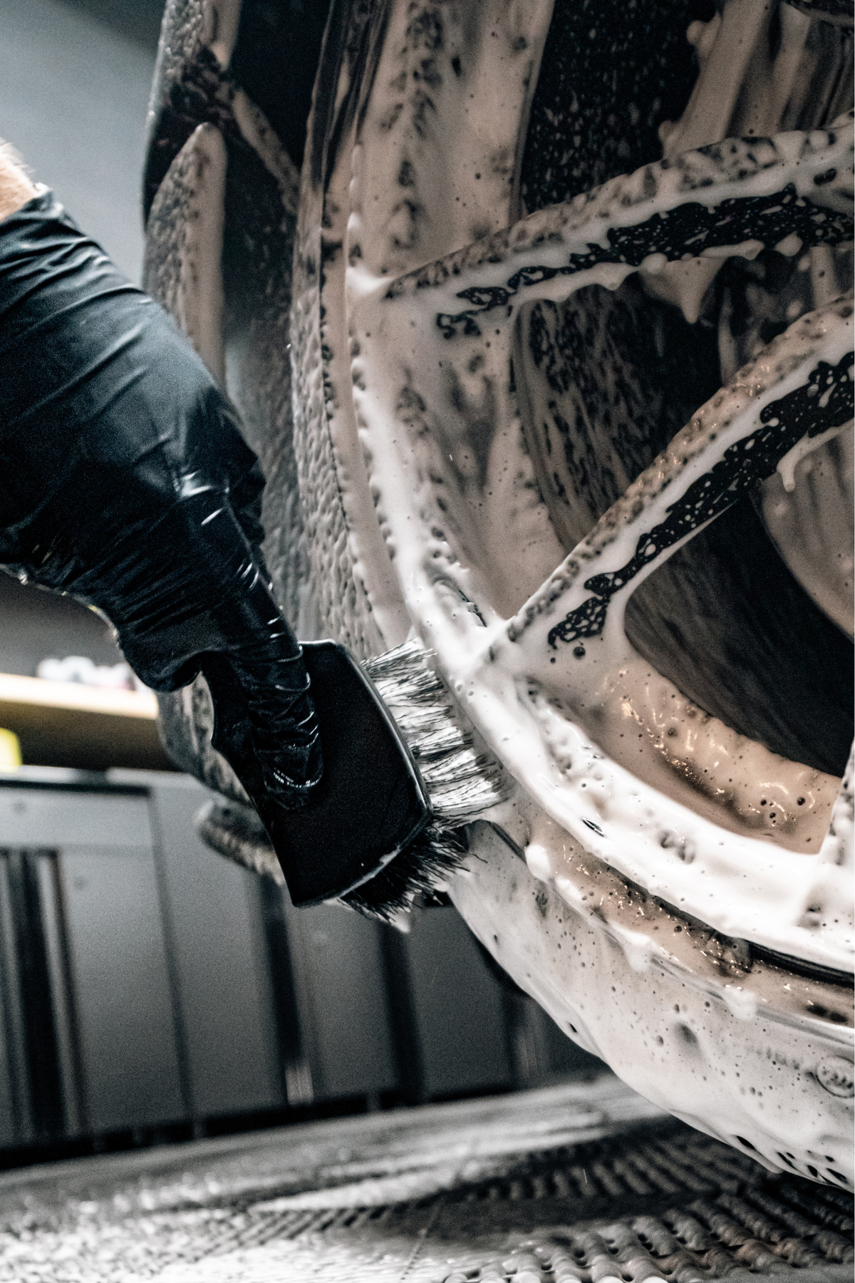 BLACKLINE® STIFF BRISTLE TIRE BRUSH in use on a soapy car wheel with a black-gloved hand on Tampa Home & Garden Store