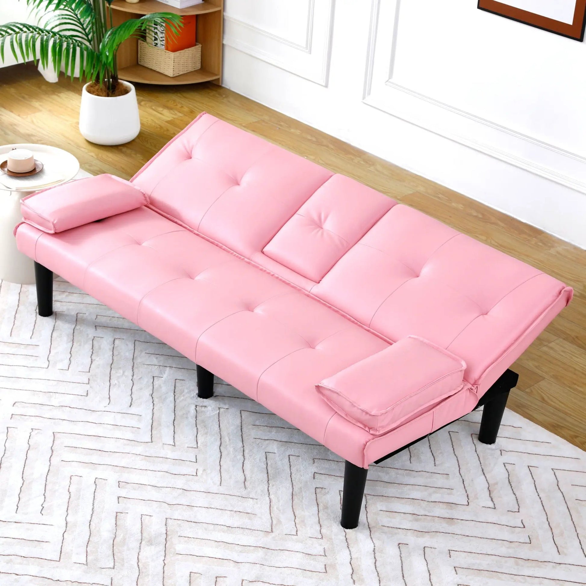 Pink tufted futon sofa bed with black legs in a bright living room on Tampa Home & Garden Store
