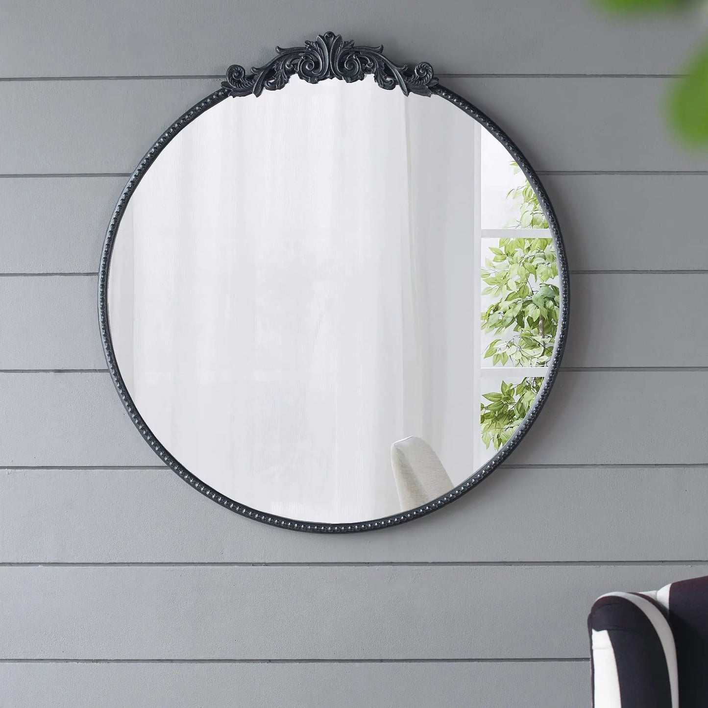 Round wall mirror with a black Baroque-inspired ornate top crest and beaded edge on Tampa Home & Garden Store