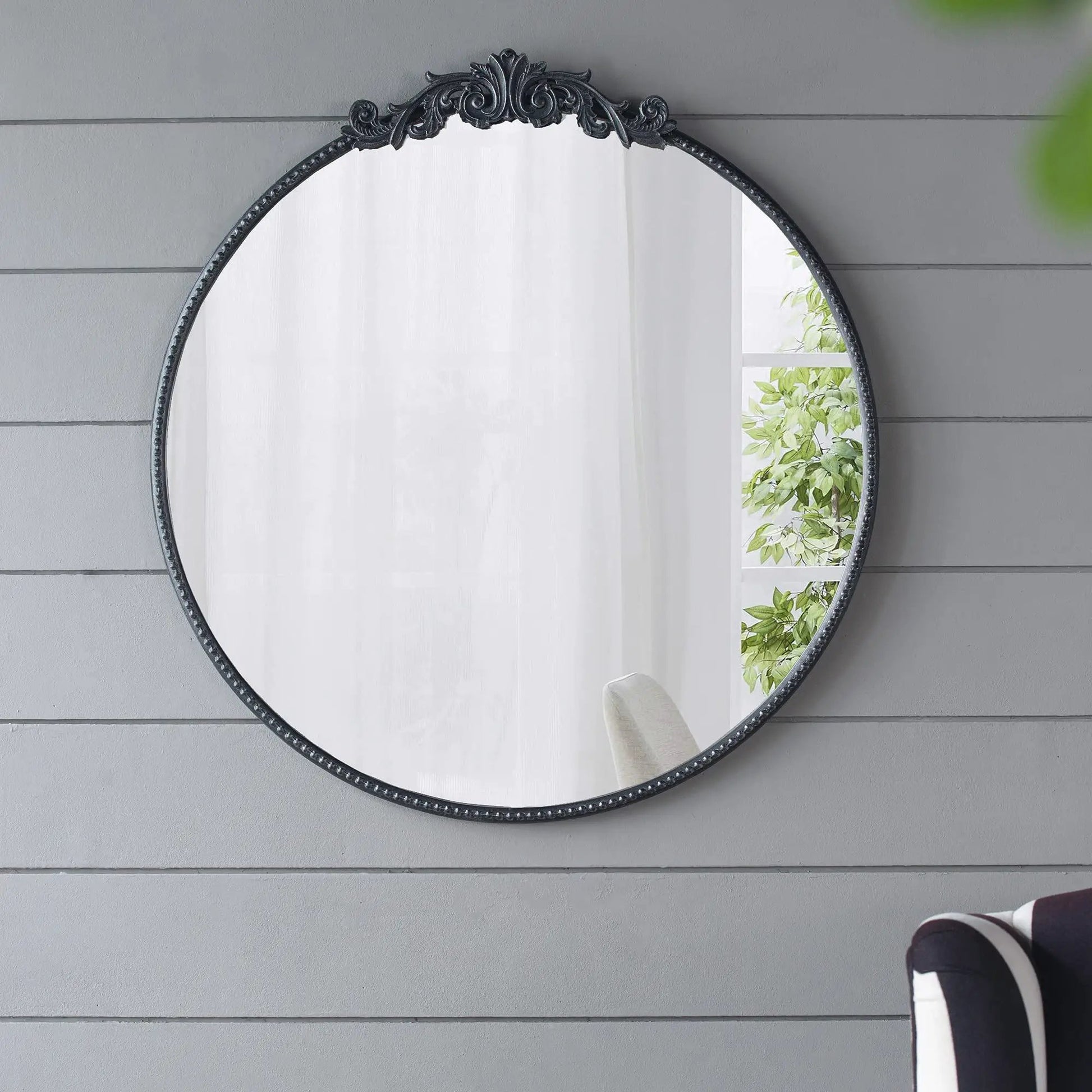 Round wall mirror with a black Baroque-inspired ornate top crest and beaded edge on Tampa Home & Garden Store