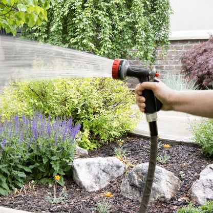 Orbit Irrigation 5-pattern zinc rear-trigger hose nozzle red and black sprays water in garden on Tampa Home & Garden Store