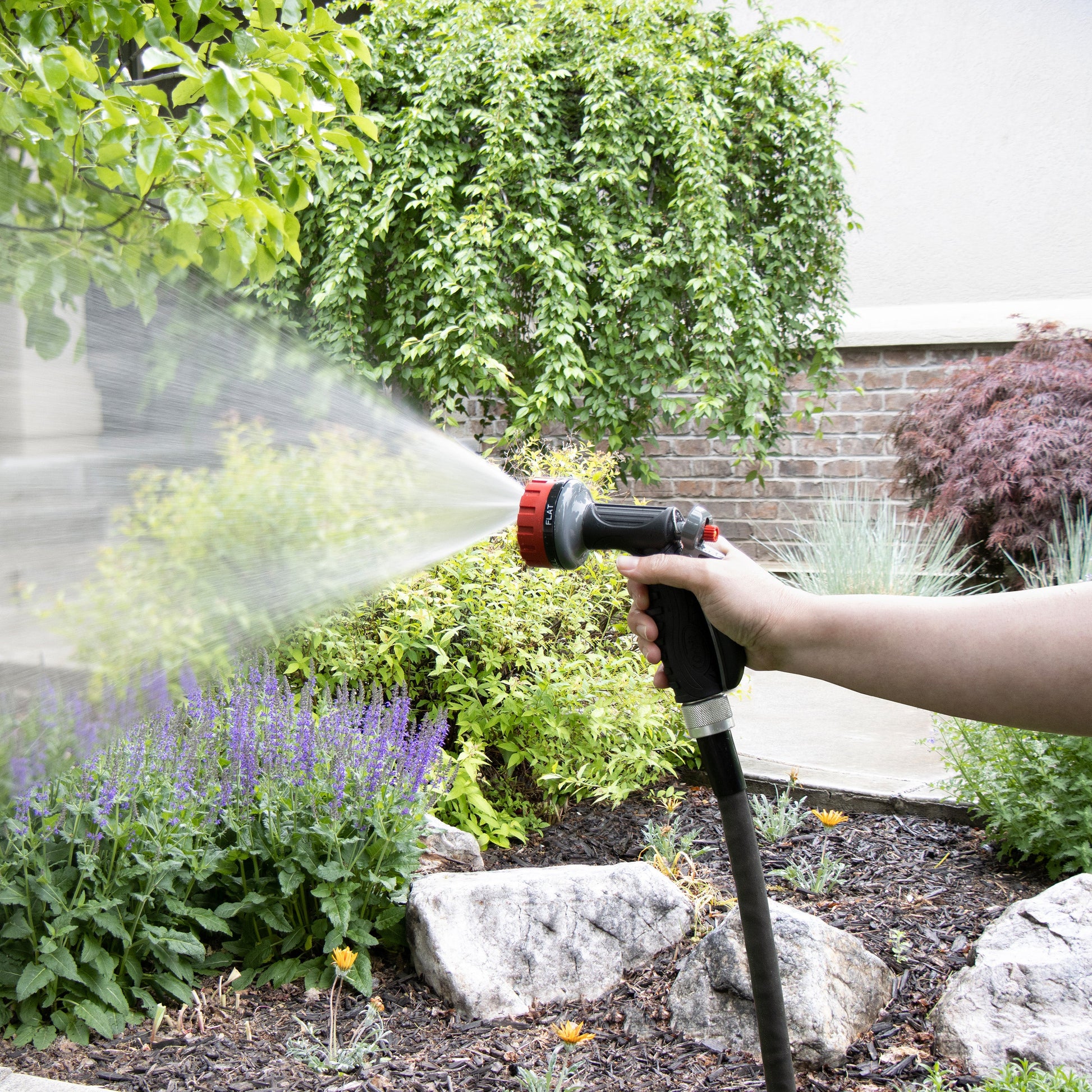 Hose End spray nozzle Orbit Irrigation 5-pattern zinc rear-trigger 26155 spraying water in garden on Tampa Home & Garden Store