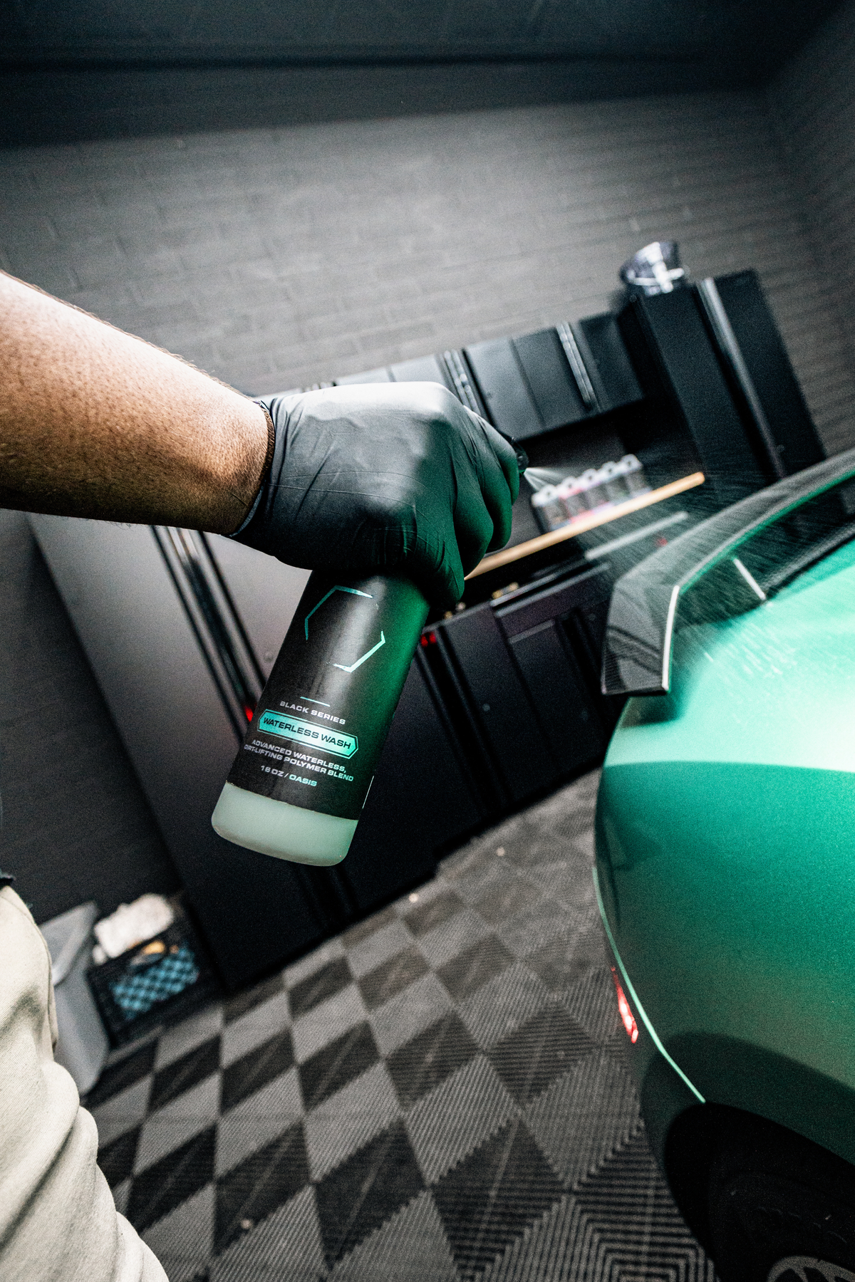BLACKLINE® Waterless Wash bottle with teal label held by gloved hand beside a green car on Tampa Home & Garden Store