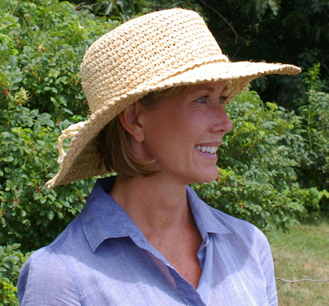 Raffia Sun Hat by Womanswork, straw wide-brim hat worn by woman outdoors on Tampa Home & Garden Store