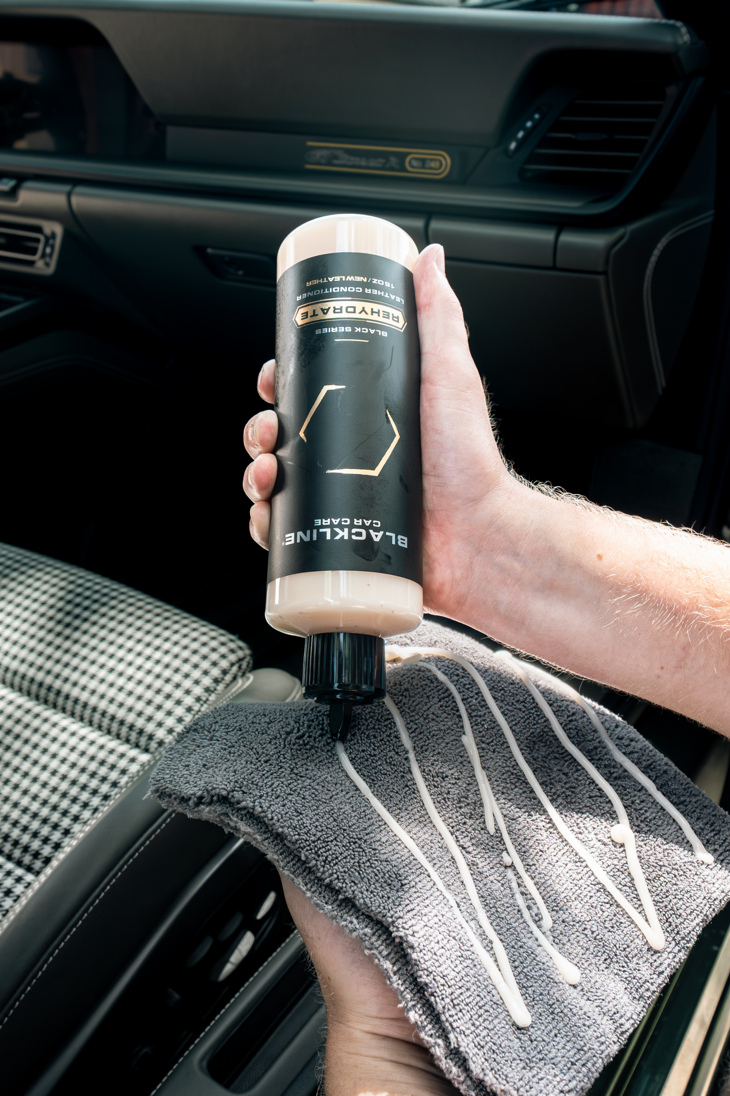 Leather conditioner Blackline Car Care bottle held in hand inside car with beige cap and towel on Tampa Home & Garden Store
