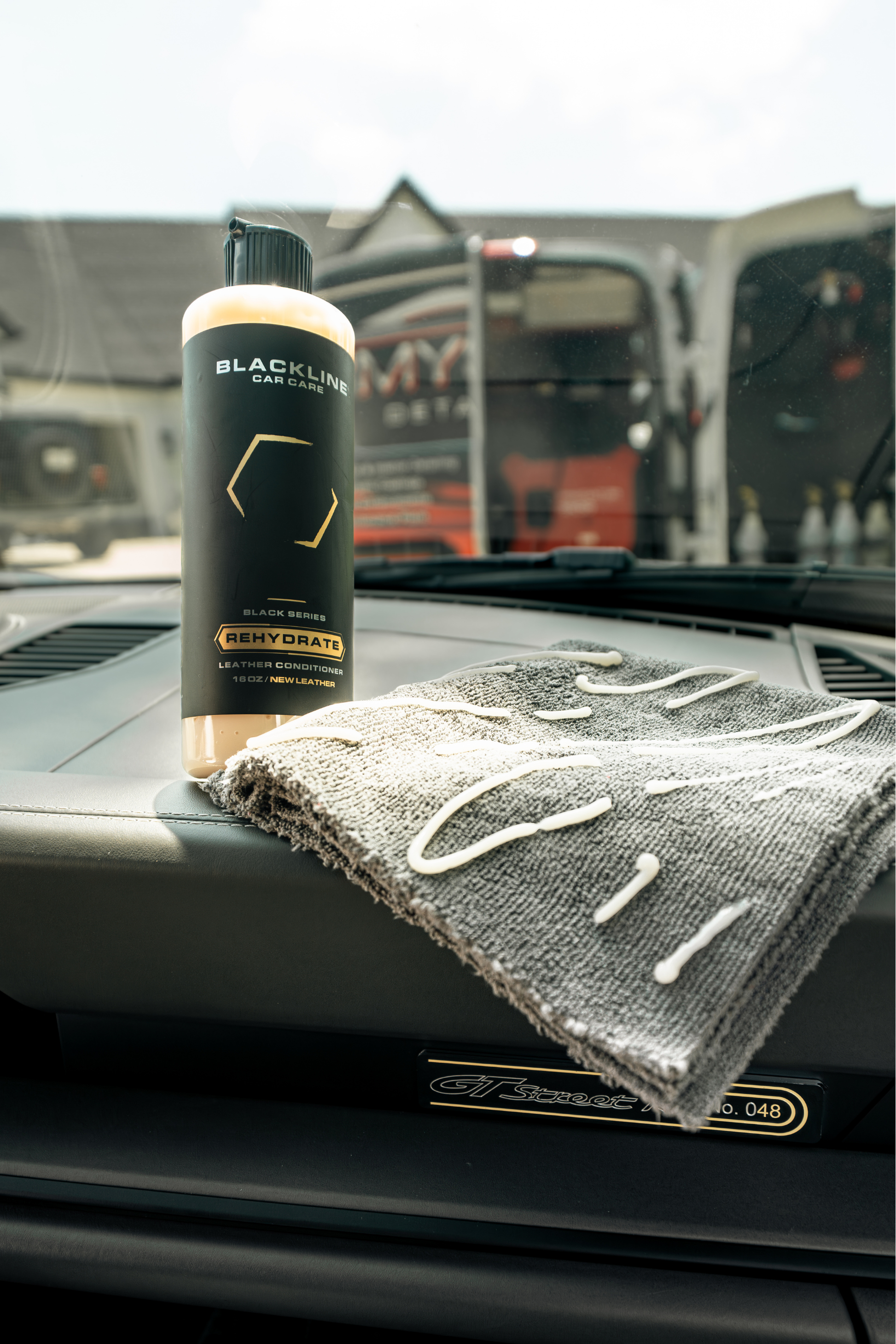 Blackline Car Care Rehydrate Leather Conditioner bottle on dashboard with gray microfiber towel on Tampa Home & Garden Store