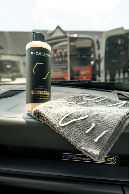 Blackline Car Care Rehydrate Leather Conditioner bottle on dashboard with gray microfiber towel on Tampa Home & Garden Store