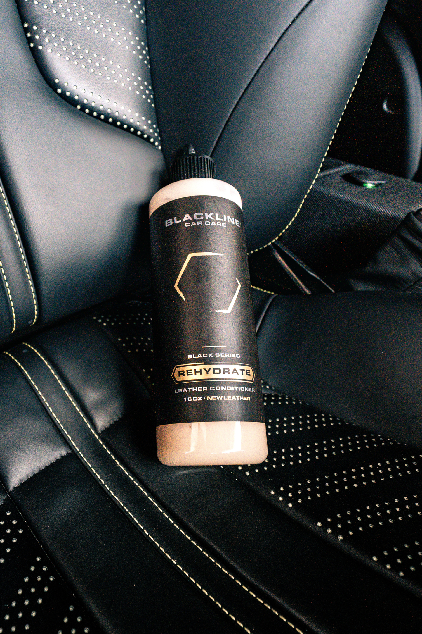 BLACKLINE Rehydrate Leather Conditioner bottle on black stitched leather car seat on Tampa Home & Garden Store