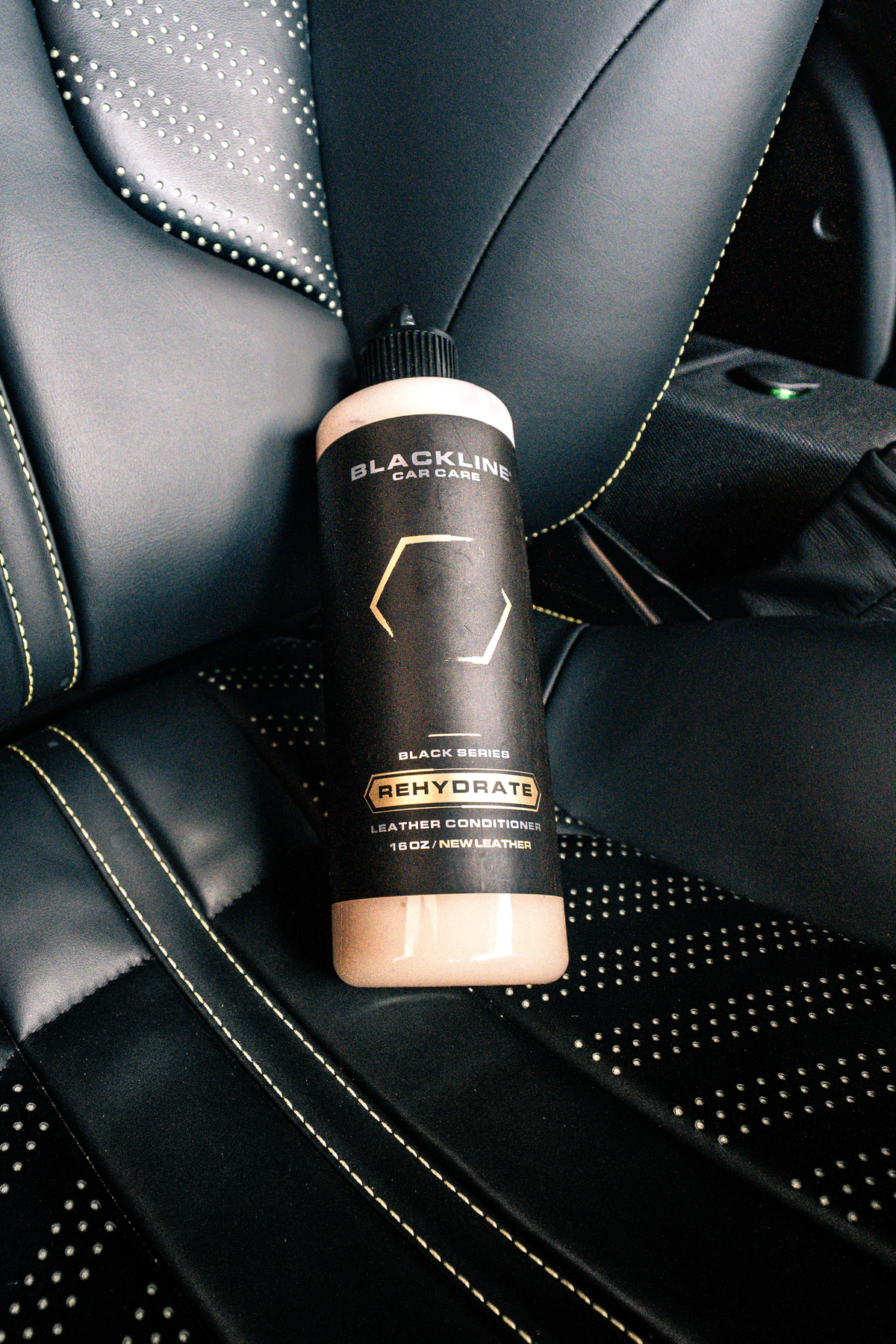 BLACKLINE Rehydrate Leather Conditioner bottle on black stitched leather car seat on Tampa Home & Garden Store