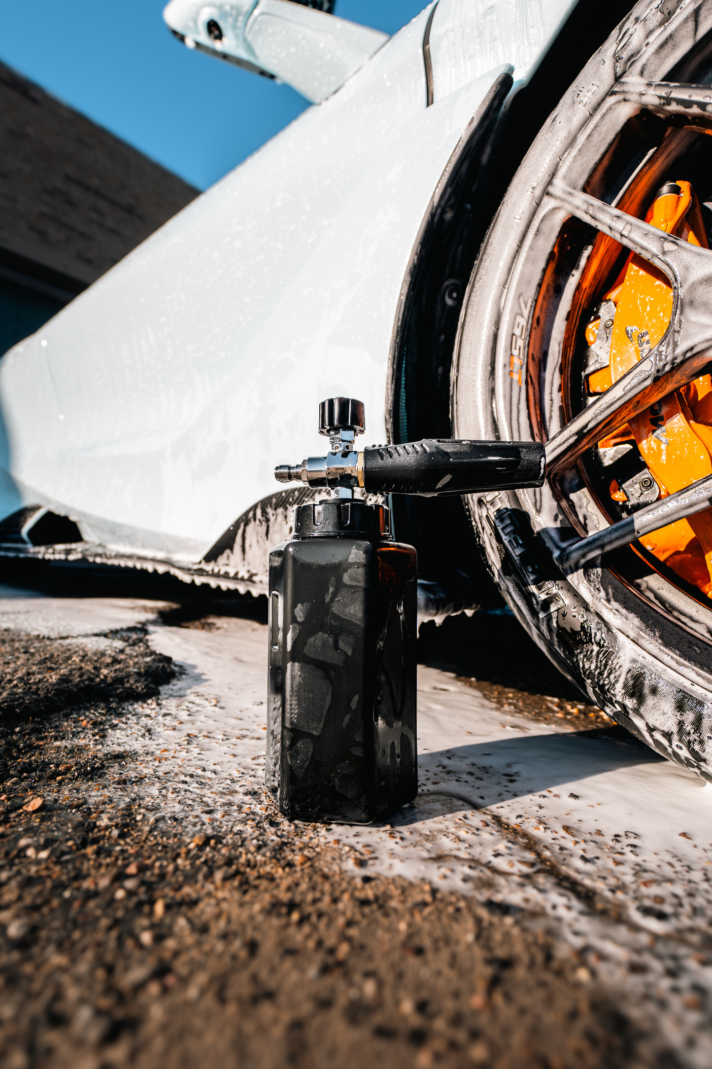 BLACKLINE Foam Cannon Pro black foam cannon with fittings beside a car with orange calipers on Tampa Home & Garden Store