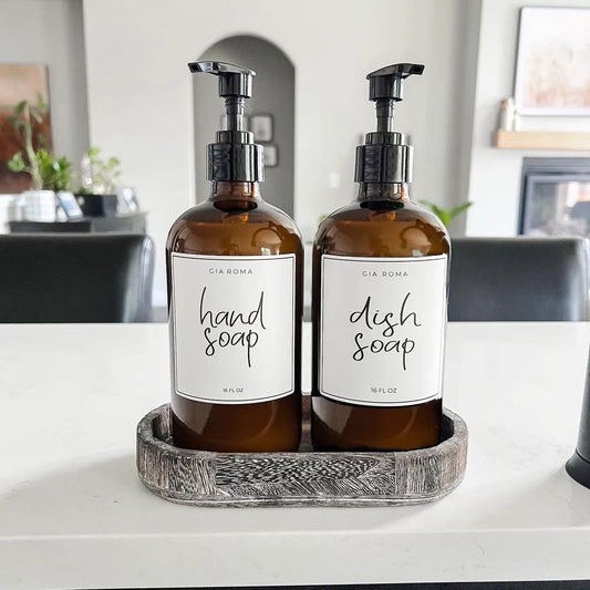 Two Gia Roma 16oz amber glass hand soap and dish soap dispensers with black pumps on a wood tray on Tampa Home & Garden Store