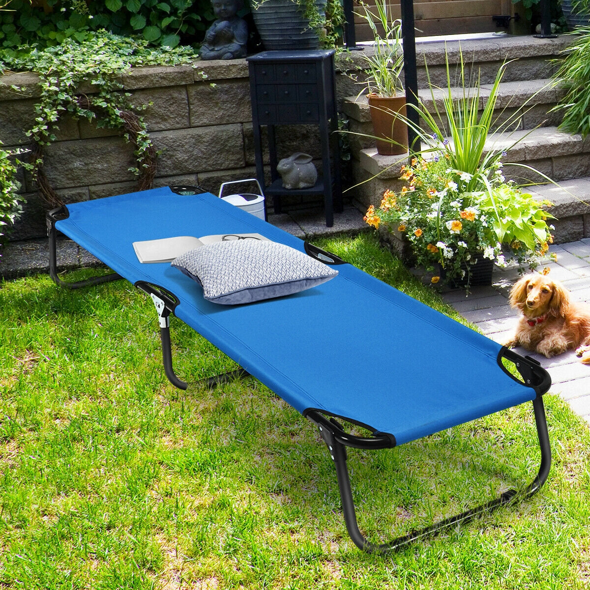 GemGear blue outdoor folding camping bed cot with pillow on lawn beside flowers and a dog on Tampa Home & Garden Store