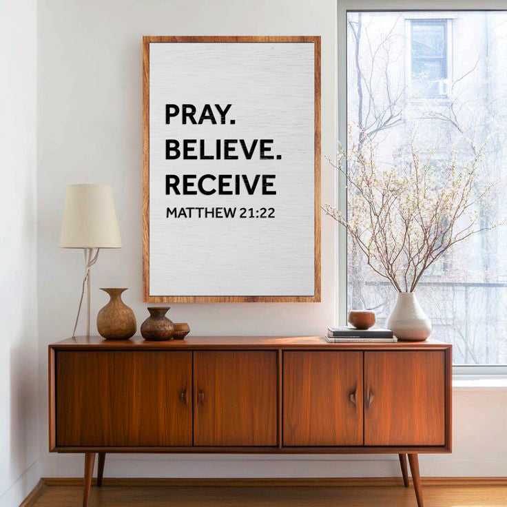 Canvas sign with Pray Believe Receive text on canvas in a wood frame above walnut console on Tampa Home & Garden Store