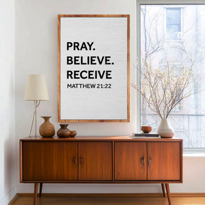 Canvas sign with Pray Believe Receive text on canvas in a wood frame above walnut console on Tampa Home & Garden Store