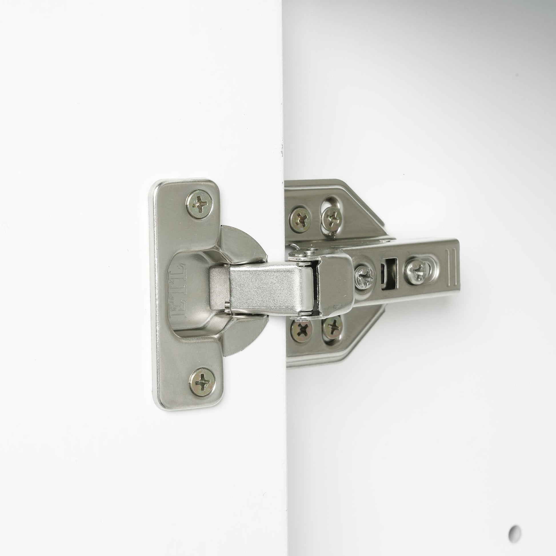 Bathroom vanity hinge closeup in brushed nickel on white cabinet with mounting screws on Tampa Home & Garden Store
