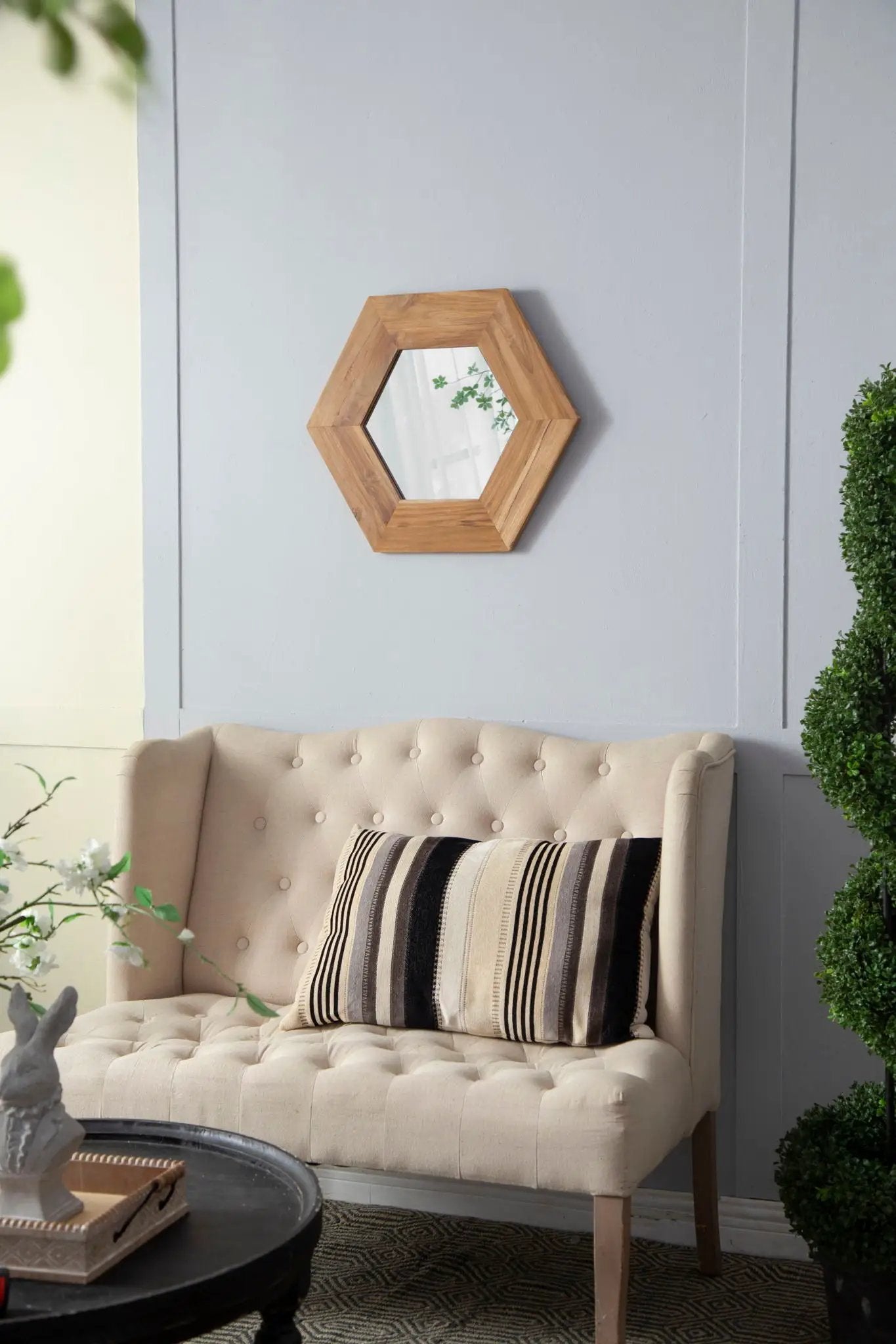 Hexagon wood-framed accent mirror on pale blue wall beside beige sofa on Tampa Home & Garden Store