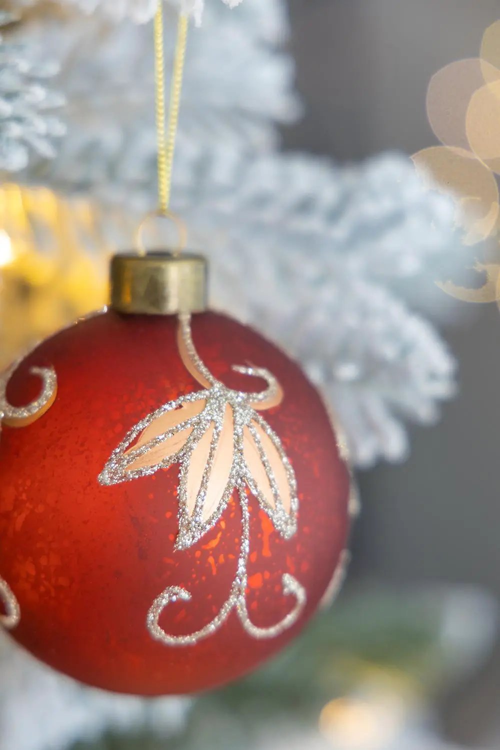 Christmas ball ornament red glass with glittery silver leaf motif hanging from a gold cap on Tampa Home & Garden Store
