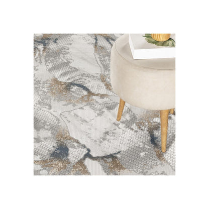 Geometrix area rug gray with 3D pattern; beige round ottoman with wooden legs and a book on Tampa Home & Garden Store