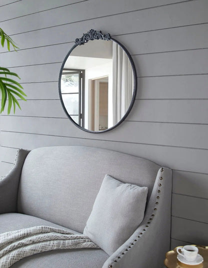 Round wall mirror with a dark baroque-inspired ornate frame on a gray shiplap wall on Tampa Home & Garden Store